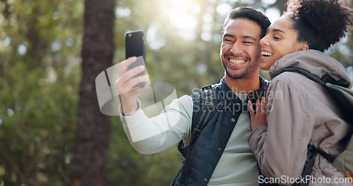 Image of Hiking, walking and young couple in forest on adventure, journey and exploring nature. Asian man and black woman trekking, walk and taking selfie in woods on smartphone enjoying freedom on weekend