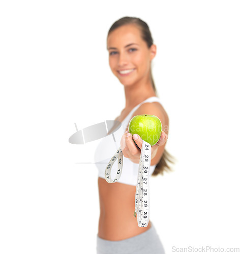 Image of Hand, apple and measuring tape with a woman in studio isolated on a white background to promote fitness, diet or weight loss. Food, nutrition and measuring with a female athlete holding a green fruit