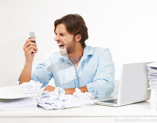 Image of Angry, frustrated business man scream into phone in studio for fail, problem or debt stress at his desk. Rude, chaos and upset worker with technology, paper and computer isolated on white background