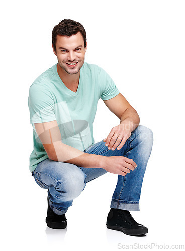 Image of Happy, smile and portrait of a man in a studio with a casual, stylish and cool trendy outfit. Handsome, young and male model with natural fashion clothes crouching while isolated by white background.