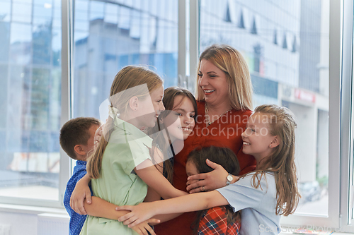 Image of A child hugging a teacher in a modern kindergarten