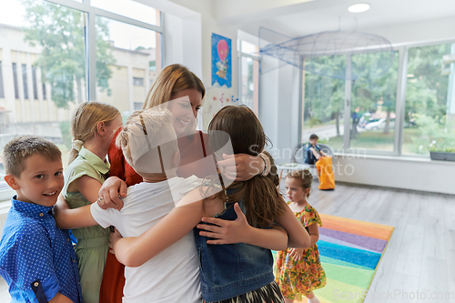 Image of A child hugging a teacher in a modern kindergarten