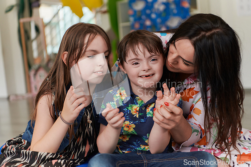 Image of A girl and a woman hug a child with down syndrome in a modern preschool institution