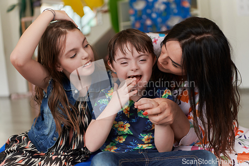 Image of A girl and a woman hug a child with down syndrome in a modern preschool institution