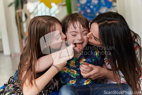 Image of A girl and a woman hug a child with down syndrome in a modern preschool institution