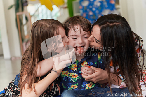 Image of A girl and a woman hug a child with down syndrome in a modern preschool institution