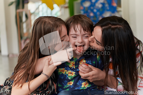 Image of A girl and a woman hug a child with down syndrome in a modern preschool institution