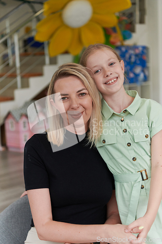 Image of A cute little girl kisses and hugs her mother in preschool