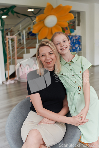 Image of A cute little girl kisses and hugs her mother in preschool