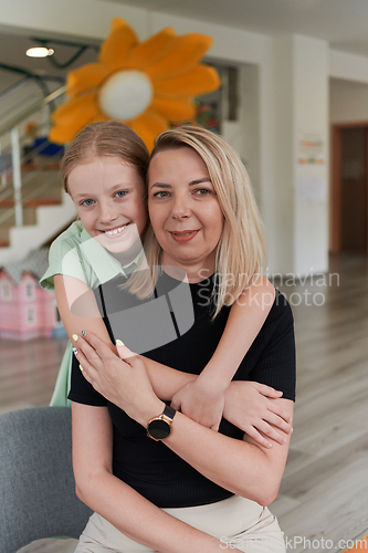 Image of A cute little girl kisses and hugs her mother in preschool