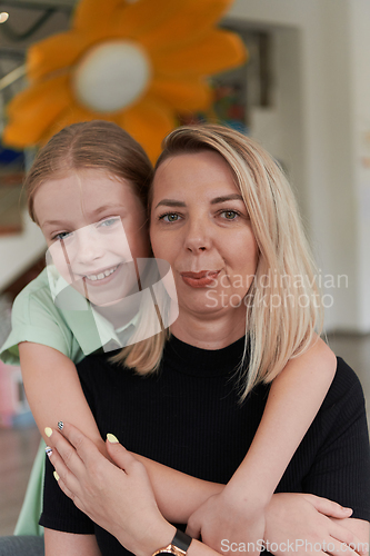 Image of A cute little girl kisses and hugs her mother in preschool