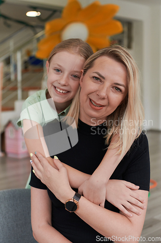 Image of A cute little girl kisses and hugs her mother in preschool