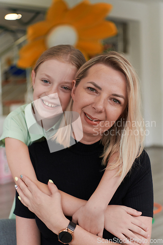 Image of A cute little girl kisses and hugs her mother in preschool