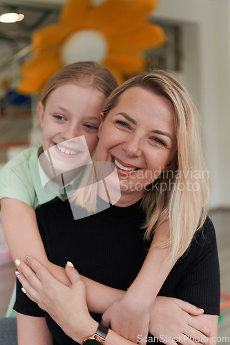 Image of A cute little girl kisses and hugs her mother in preschool