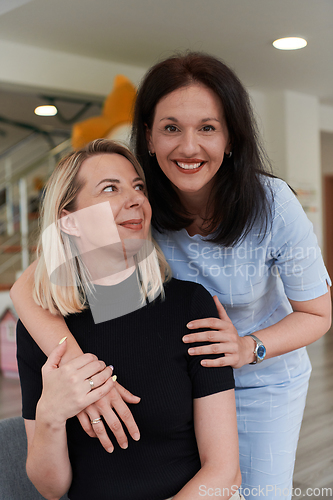 Image of Two women share a heartfelt embrace while at a preschool, showcasing the nurturing and supportive environment for learning and growth