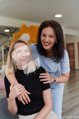 Image of Two women share a heartfelt embrace while at a preschool, showcasing the nurturing and supportive environment for learning and growth