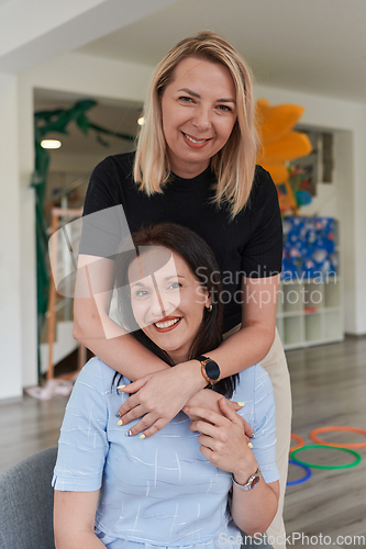 Image of Two women share a heartfelt embrace while at a preschool, showcasing the nurturing and supportive environment for learning and growth