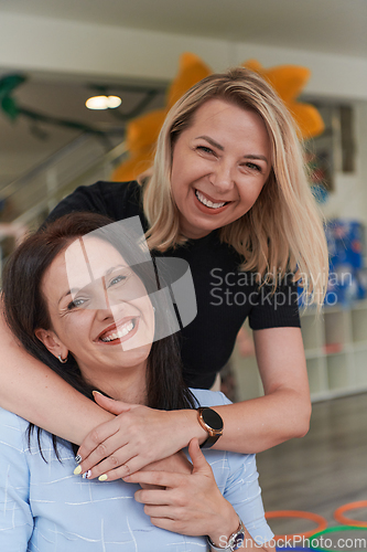 Image of Two women share a heartfelt embrace while at a preschool, showcasing the nurturing and supportive environment for learning and growth