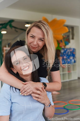 Image of Two women share a heartfelt embrace while at a preschool, showcasing the nurturing and supportive environment for learning and growth