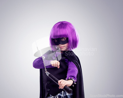 Image of Kid, costume girl or vigilante in studio portrait with nunchaku, fantasy or creative comic clothes. Kid, superhero aesthetic, mask and creative for martial arts, villain or cosplay by gray background