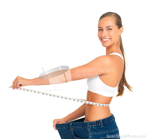 Image of Portrait, waist and weight loss with a woman measuring her tummty in studio isolated on a white background. Fitness, diet and health with a female holding a tape measure to track her weightloss