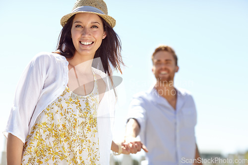 Image of Young couple holding hands with smile for summer vacation, travel or journey together in the outdoors. Portrait of beautiful woman leading her boyfriend by the hand on a sunny day for the holiday