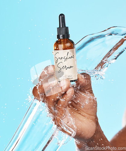 Image of Serum, skincare and hand of a man with a water splash for an anti aging product, beauty and hair growth secret on a blue background in studio. Cosmetic, marketing and model with an oil for acne