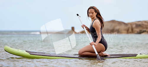 Image of Surfer, fitness and woman in ocean with surfboard and paddle, swimwear and focus with sport outdoor and nature. Beach, exercise and young female surfing, waves and adventure with extreme sports