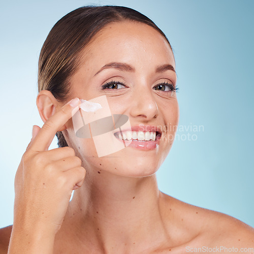 Image of Skincare, beauty and portrait of a woman with face cream for health, wellness and natural face routine. Cosmetic, happy and model with facial lotion, spf or creme isolated by a blue studio background