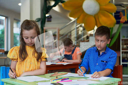 Image of Cute girl and boy sit and draw together in preschool institution