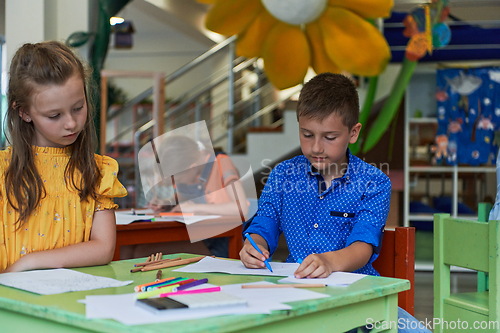 Image of Cute girl and boy sit and draw together in preschool institution