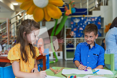 Image of Cute girl and boy sit and draw together in preschool institution