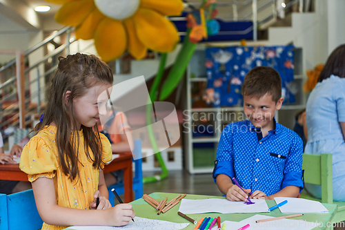 Image of Cute girl and boy sit and draw together in preschool institution