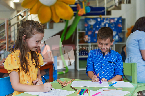 Image of Cute girl and boy sit and draw together in preschool institution