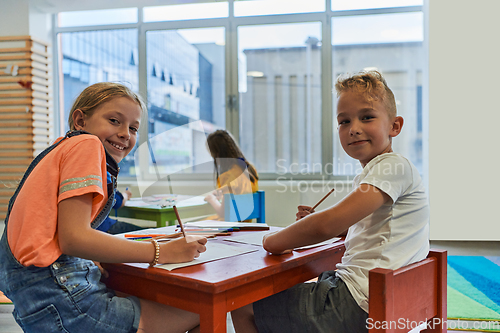 Image of Cute girl and boy sit and draw together in preschool institution