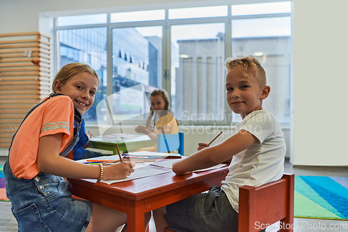 Image of Cute girl and boy sit and draw together in preschool institution