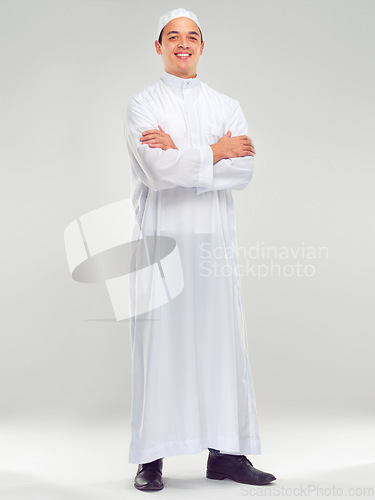 Image of Islamic man, smile portrait and muslim fashion standing in white background for Arabic culture. Young person, smile and religion faith, worship or religious mindfulness standing isolated in studio