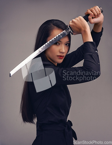 Image of Portrait, sword and samurai with a model woman in studio on a gray background for martial arts or combat. Training, fantasy and weapon with an asian ninja ready to defend using self discipline