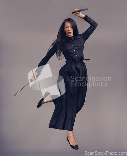 Image of Ninja, swords and woman samurai in a studio jumping for a martial arts or assassin fighter skill. Fantasy, cosplay and female model in a warrior costume with blade isolated by a gray background.