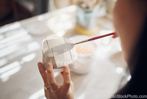 Image of Woman hands, pottery studio and painting cup in workshop for sculpture, creative manufacturing or design. Painter, ceramics product and brush process, artistic pattern or production in small business