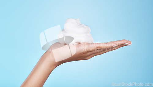 Image of Skincare, wellness and hands with foam on blue background for treatment, grooming and body care. Cosmetics, spa aesthetic and palm with shaving cream, soap and cleaning products isolated in studio