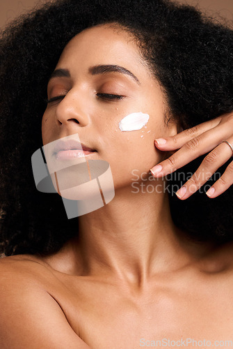 Image of Cosmetics, black woman and cream for organic facial collagen and brown studio background. Jamaican female, girl and face lotion for healthy, smooth or soft skin for spa treatment, self care or luxury