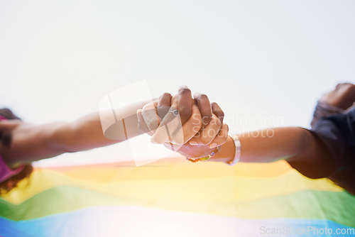 Image of LGBTQ flag, rainbow and couple holding hands for gay pride, lesbian support or human rights protest. LGBT community, sky and African black people together in love, partnership and equality below view