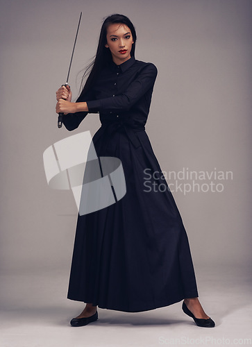 Image of Samurai, sword and portrait of a ninja in a studio with a martial arts or assassin fighter skill. Fantasy, cosplay and female model in a warrior costume with a machete posing by a gray background.