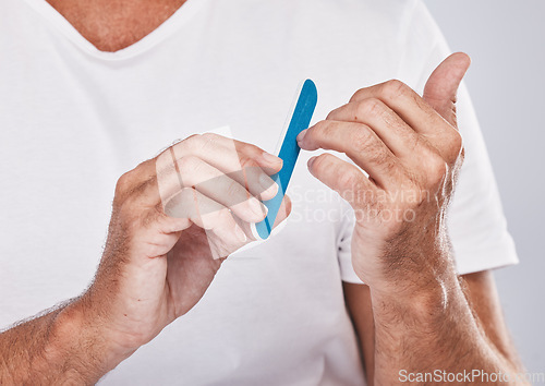 Image of Hands, nail file and grooming with a man in studio on a gray background for beauty while filing his finger nails. Manicure, wellness and cosmetics with a male taking care of his personal hygiene