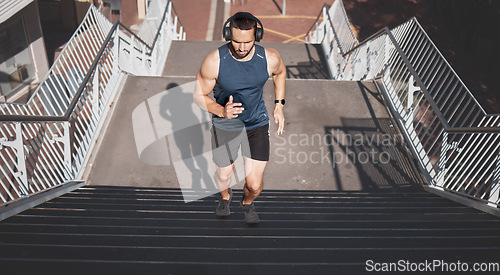 Image of Urban fitness, man running on stairs and listening to music on headphones on outdoor exercise in Los Angeles. Health, motivation and a California city runner on steps for marathon training in morning