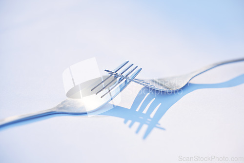 Image of Dinner, shadow and forks on a table for partnership, teamwork and collaboration on a blue studio background. Creative, design and kitchen utensils with reflection of solidarity and team work