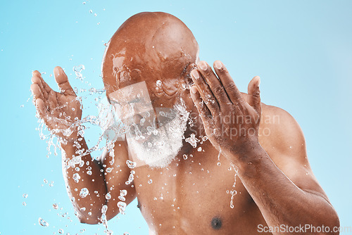 Image of Black man cleaning face with water splash, healthy skincare on studio blue background for shower, cosmetics and body care transformation. Male model, senior beauty and facial hygiene with clean water