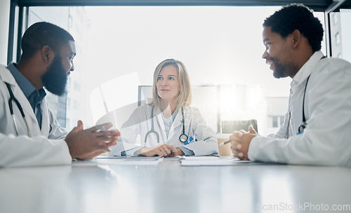 Image of Healthcare, meeting and team of doctors talking in hospital, clinic or health care facility boardroom. Teamwork, communication and medical workers in discussion, conversation and speaking with paper