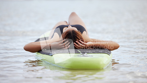 Image of Relax, woman or surfer on water at a beach on holiday vacation resting on a surfboard in Bali. Freedom, thinking or healthy sports girl relaxing body in calm nature, sea or peaceful ocean in summer